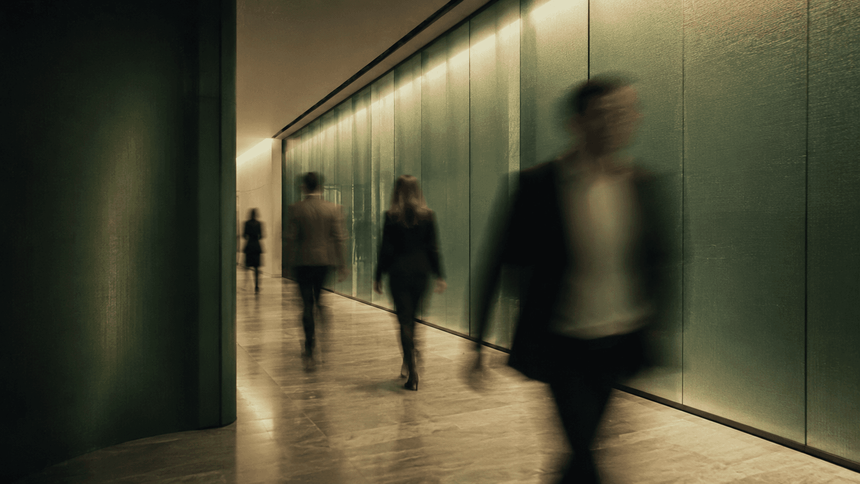 People moving through a softly lit office corridor